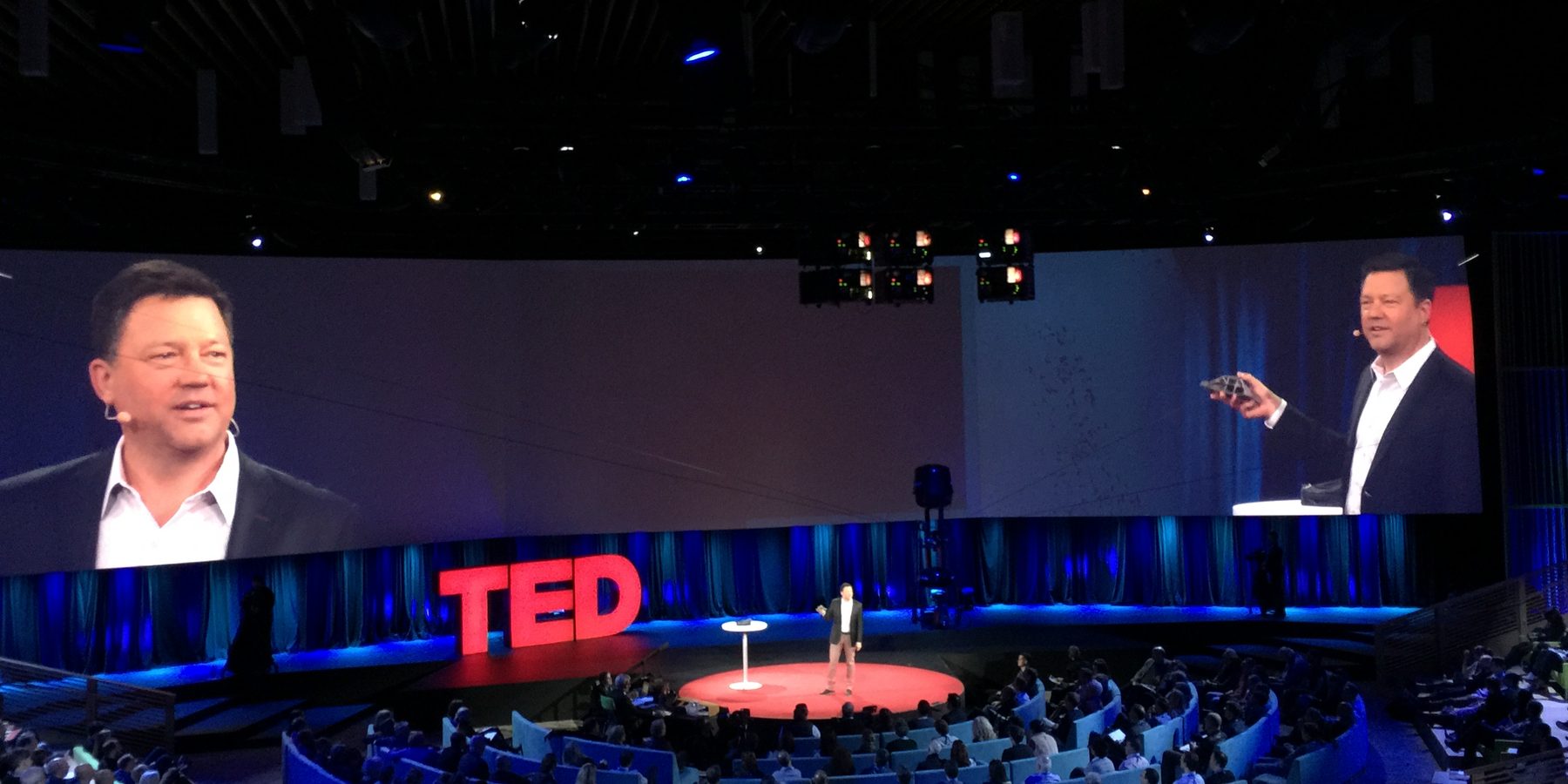 Rick Smith on the TED main stage, with his image on the screens above the audience