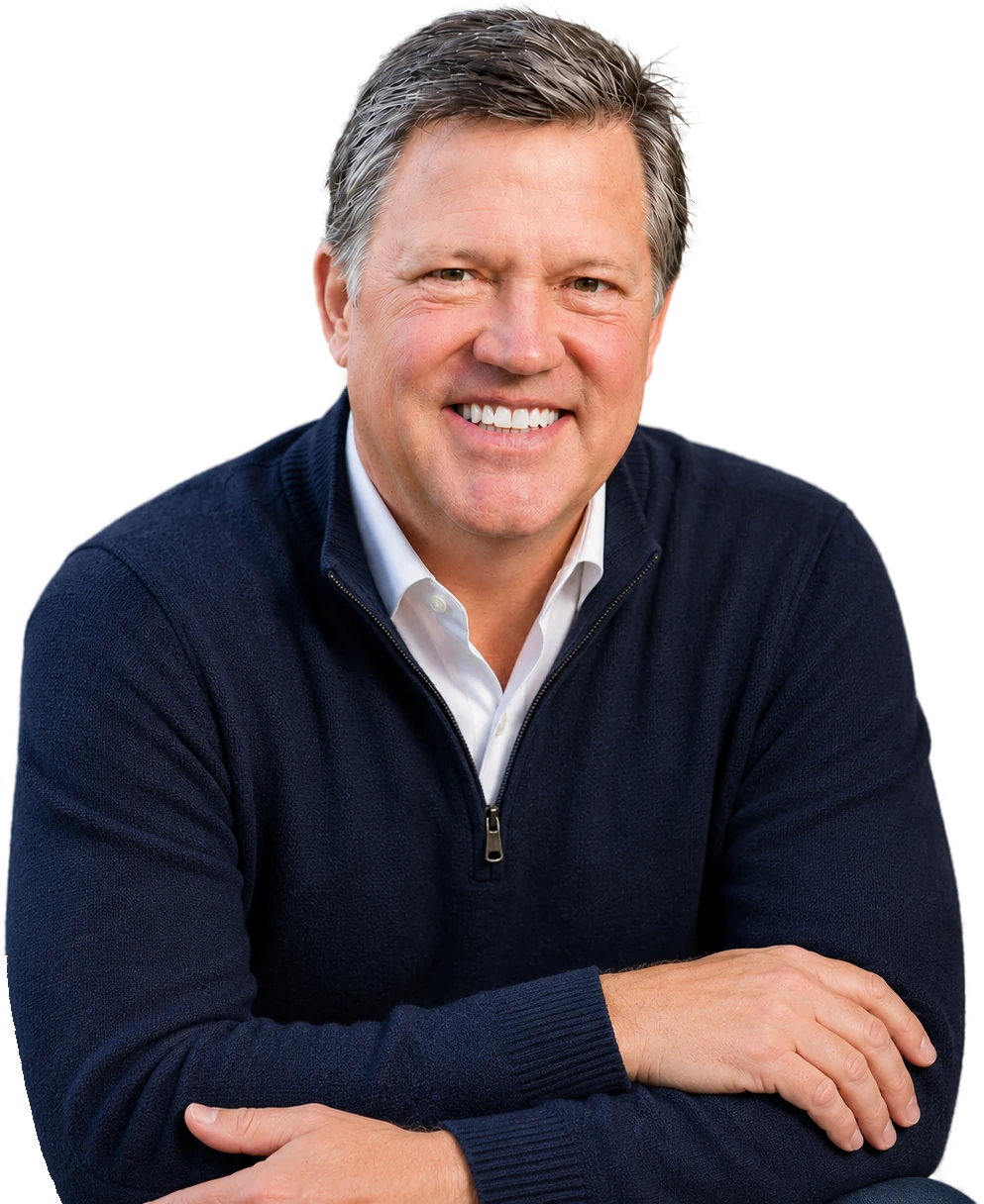 Rick Smith smiling, in a navy sweater with his arms folded